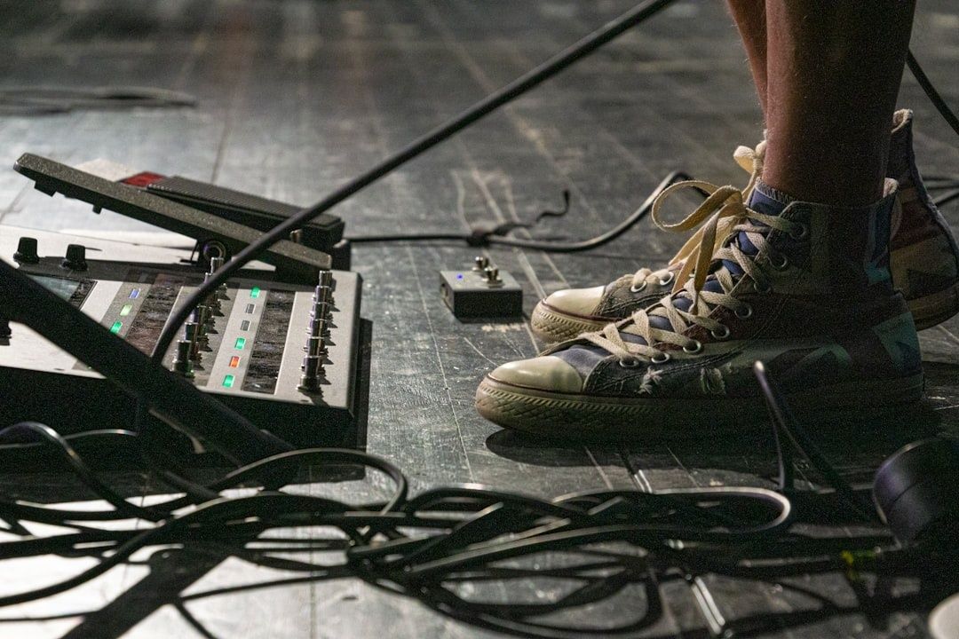 Sneaker neben Effektpedalen und Kabeln auf einer Konzertbühne
