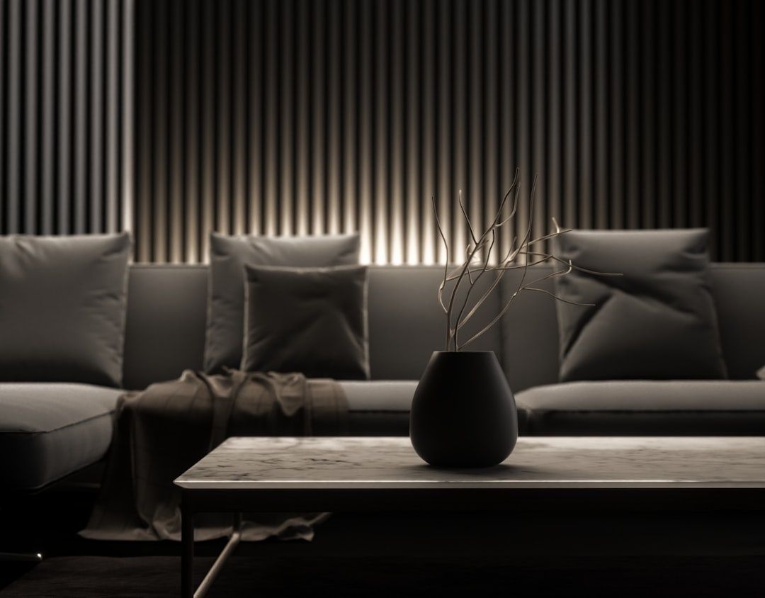 Gedämpft beleuchtetes Wohnzimmer mit Sofa, Couchtisch und schwarzer Vase